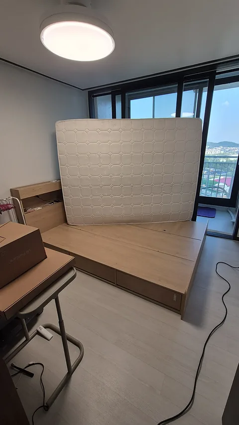 세워 둔 매트리스와 침대 프레임 상판
